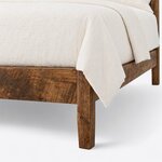 Footboard close-up of a farmhouse panel bed, showing the deep footboard meeting a tapered square leg and the side rail.