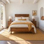 Front room view of a farmhouse panel bed with a low footboard, in a white plaster bedroom with an arched niche.