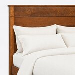 Headboard close-up of a farmhouse panel bed, showing horizontal plank panels under an overhanging cap and a square post.