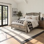 Diagonal angled room view showing the left side of a rustic panel bed with a low capped footboard, in a shiplap bedroom.