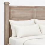 Headboard close-up of a farmhouse panel bed, showing recessed panels split by a center stile and a stepped post cap.