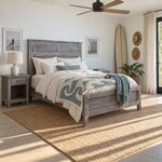 Diagonal angled room view showing the right side of a farmhouse panel bed with a louvered headboard, in a coastal bedroom.