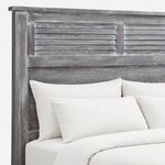 Headboard close-up of a farmhouse panel bed, showing louvered panels split by a center stile under an overhanging cap rail.