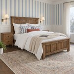 Diagonal angled room view showing the right side of a Craftsman panel bed with a panel footboard, in a blue-striped bedroom.