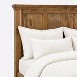 Headboard close-up of a Craftsman panel bed, showing recessed plank panels framed by stiles under a crown-molded cap.