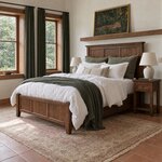 Diagonal angled room view showing the left side of a Shaker panel bed with tapered legs, in a terracotta-tiled bedroom.