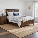 Diagonal angled room view showing the right side of a Shaker panel bed with a panel footboard, in a wainscoted bedroom.