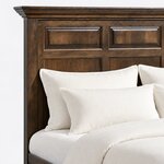 Headboard close-up of a mantel panel bed, showing the layered crown-molded mantel above raised panels and a square post.