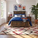 Front room view of a mantel panel bed with a tall paneled headboard, in a white bedroom with a gallery wall.