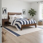 Diagonal angled room view showing the right side of a modern panel bed with a low footboard, in a bright white bedroom.