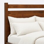 Headboard close-up of a modern panel bed, showing the top rail, open slot and broad solid panel framed by a square post.