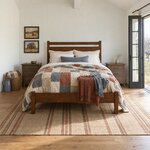 Front room view of a modern panel bed with an open-slot headboard, in a vaulted farmhouse bedroom with French doors.