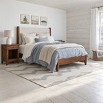 Diagonal angled room view showing the right side of a modern upholstered bed with tapered legs, in a log cabin bedroom.