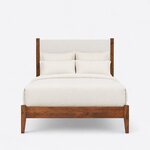 Front view of a modern upholstered bed, showing a tall upholstered headboard between square posts and a low plain footboard.