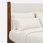 Headboard close-up of a modern upholstered bed, showing the smooth upholstered panel framed by a square wood post.