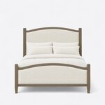 Front view of an Art Deco upholstered bed, showing matching arched boards framed in wood on tapered legs with metal caps.