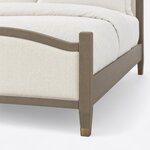 Footboard close-up of an Art Deco upholstered bed, showing the arched rail, square post and metal-capped tapered leg.
