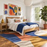 Diagonal angled room view showing the right side of a modern platform bed with tapered legs, in a gallery-wall bedroom.