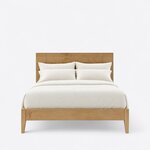 Front view of a modern platform bed, showing a broad plank headboard, a low plain footboard and gently tapered legs.