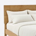 Headboard close-up of a modern platform bed, showing the flat plank panel with breadboard-style ends and square corners.