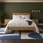 Front room view of a modern platform bed with a flat plank headboard and tapered legs, in an olive-green bedroom.