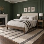 Diagonal angled room view showing the left side of a modern upholstered bed with tapered legs, in a green-paneled bedroom.