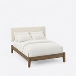High angled view of a modern upholstered bed, looking down on the low rectangular frame, tapered legs and plain headboard.