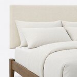 Headboard close-up of a modern upholstered bed, showing a smooth untufted panel with square corners above the low frame.