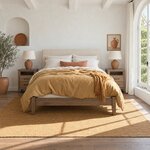Front room view of a modern upholstered bed with a rectangular headboard, in a white plaster bedroom with an arched window.