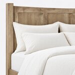 Headboard close-up of a modern panel bed, showing recessed flat panels under a gently curved top rail beside a square post.