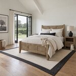 Diagonal angled room view showing the left side of a modern panel bed with a three-panel footboard, in a farmhouse bedroom.