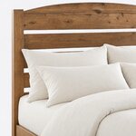 Headboard close-up of a modern slat bed, showing an arched top board, open gaps between the slats and a square post.