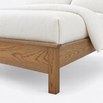 Footboard close-up of a minimalist slat bed, showing the overhanging cap rail above a plain panel and a straight square leg.