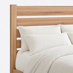 Headboard close-up of a minimalist slat bed, showing wide horizontal slats with open gaps between flat-topped square posts.