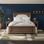 Front room view of a transitional panel bed with a button-tufted arched headboard insert, in a navy-walled bedroom.
