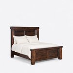 Diagonal angled view showing the right side of a farmhouse panel bed, with a shiplap headboard and a two-panel footboard.