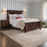 Diagonal angled room view showing the right side of a farmhouse panel bed with a shiplap headboard, in a striped bedroom.