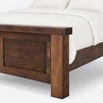 Footboard close-up of a farmhouse panel bed, showing the thick overhanging cap, a flat recessed panel and a square block leg.