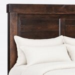 Headboard close-up of a farmhouse panel bed, showing horizontal shiplap boards in framed bays under a thick overhanging cap.