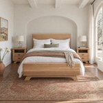 Front room view of a contemporary panel bed with splayed feet, in a white plaster bedroom with an arched niche.