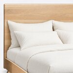 Headboard close-up of a contemporary panel bed, showing a smooth wide slab with softly rounded corners and eased edges.
