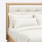 Headboard close-up of a contemporary upholstered bed, showing the button-tufted panel inset in a frame with rounded corners.