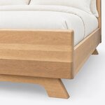Footboard close-up of a contemporary upholstered bed, showing the rounded footboard edge, side rail and an angled foot.