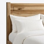 Headboard close-up of a minimalist panel bed, showing routed rectangular grooves and a flat-topped square post.