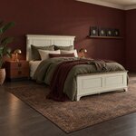 Diagonal angled room view showing the right side of a traditional panel bed with a low footboard, in a deep red bedroom.