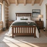 Front room view of a rustic slat bed with overhanging cap rails, in a log cabin bedroom with a beamed ceiling.