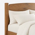 Headboard close-up of a contemporary short post bed, showing the arched solid panel with a notched corner at a square post.