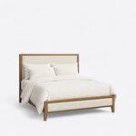 Diagonal angled view showing the right side of a modern upholstered bed, with a wood-framed headboard and a low footboard.