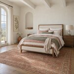 Diagonal angled room view showing the left side of a modern upholstered bed with a low footboard, in a plaster bedroom.