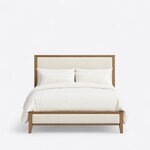 Front view of a modern upholstered bed, showing a tall framed headboard and a low framed footboard on tapered foot legs.